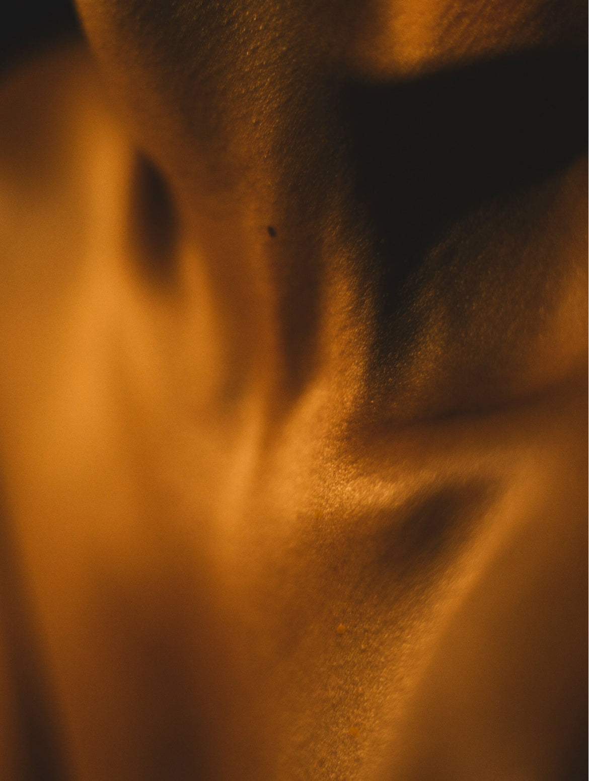 Warm amber light on skin, body oil mood image